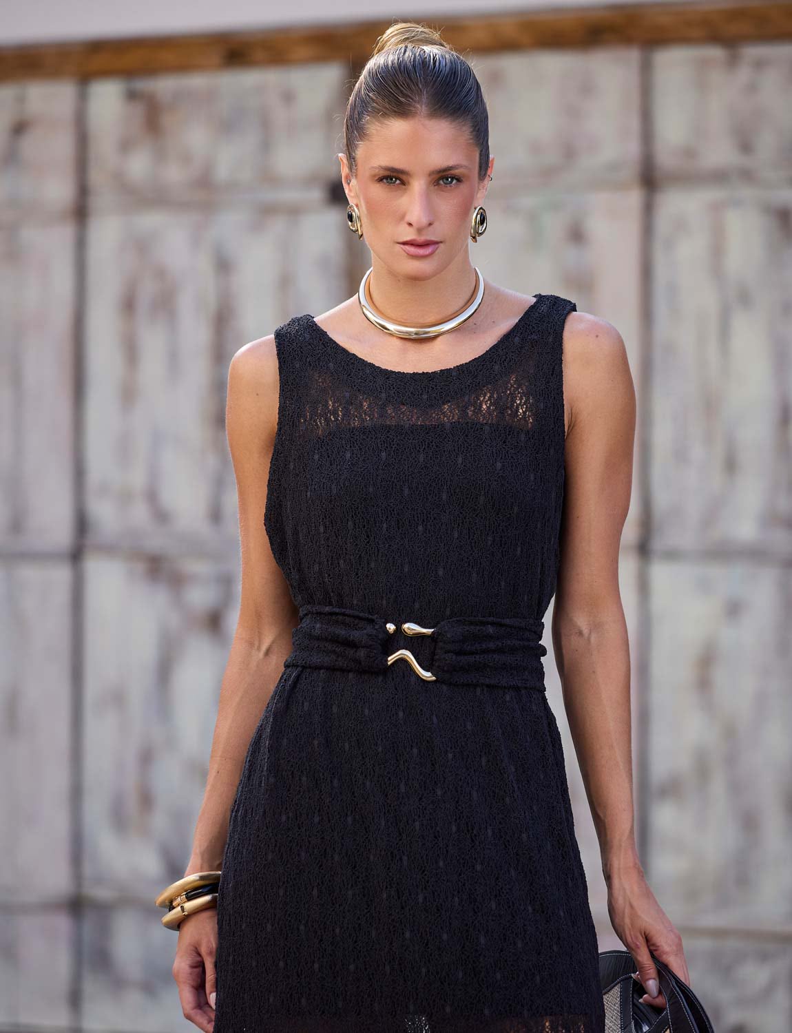 Mulher usando vestido regata longo de renda preta da Kalini com cinto marcando a cintura em produção elegante.