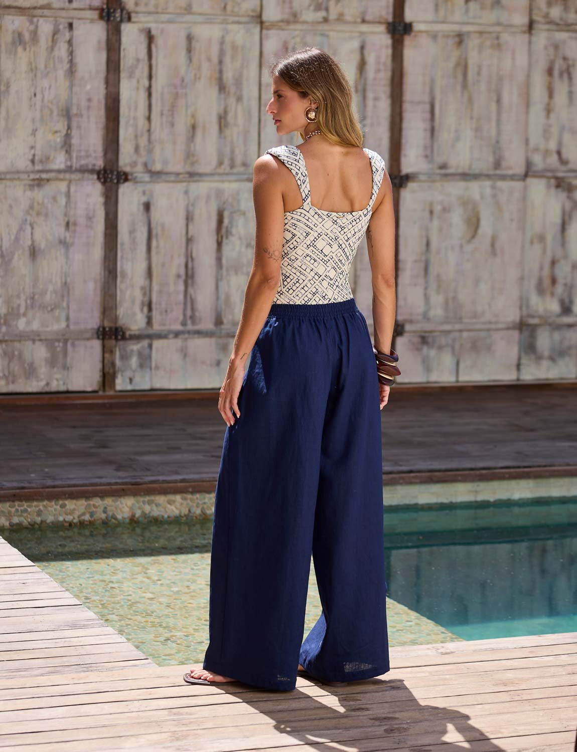 Mulher usando calça ampla e fluida azul marinho Kalini com caimento elegante