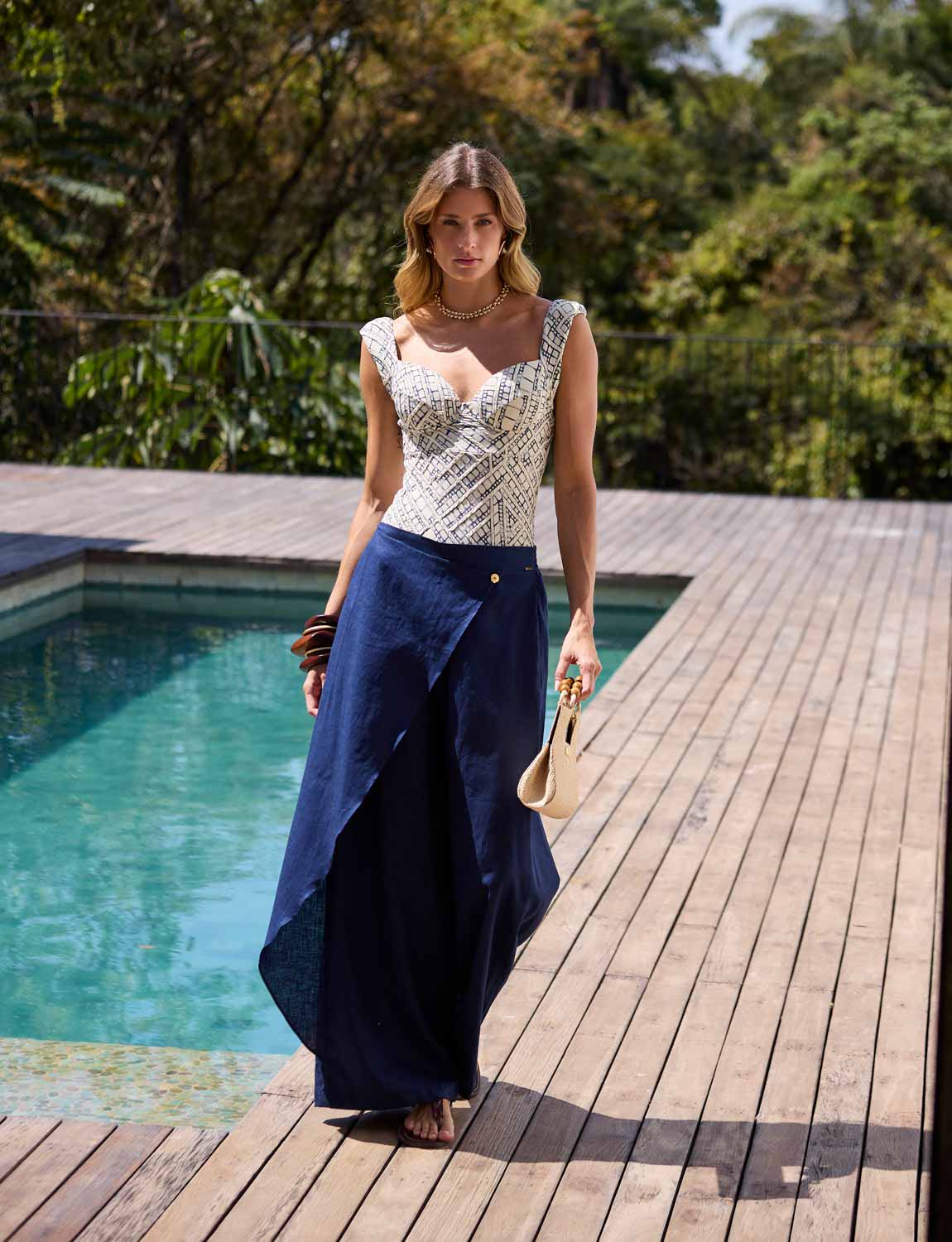 Mulher usando calça assimétrica azul marinho Kalini com modelagem ampla e detalhe frontal transpassado