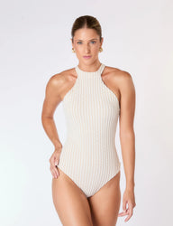 Mulher vestindo maiô branco texturizado, posando com feição suave contra fundo branco.