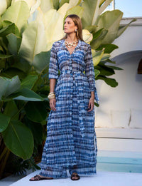 Chemise Maxi Manga Longa Prisma Kalini em tecido Panarea com faixa na cintura em cenário resort tropical