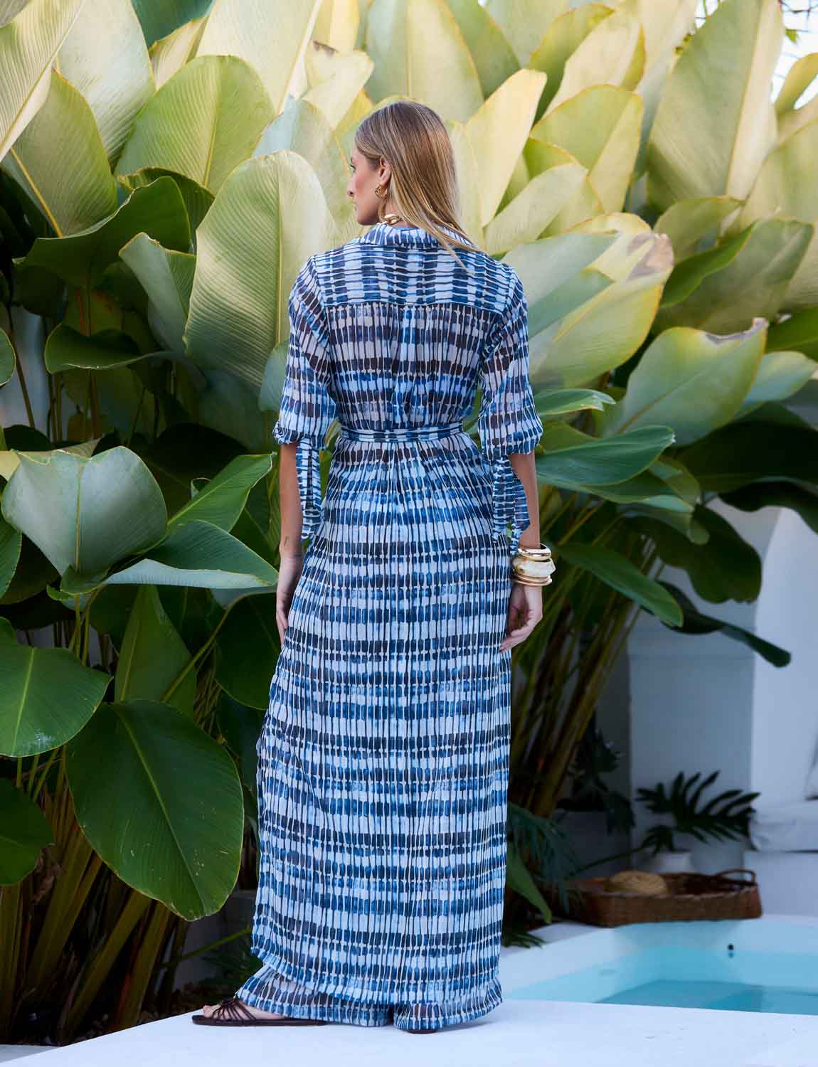 Chemise Maxi Manga Longa Prisma Kalini em tecido Panarea com faixa na cintura em cenário resort tropical