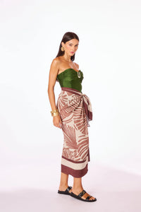 Mulher usando top verde tomara que caia com detalhe em fivela e saia pareô estampada marrom e bege, look resortwear elegante e sofisticado da marca Kalini