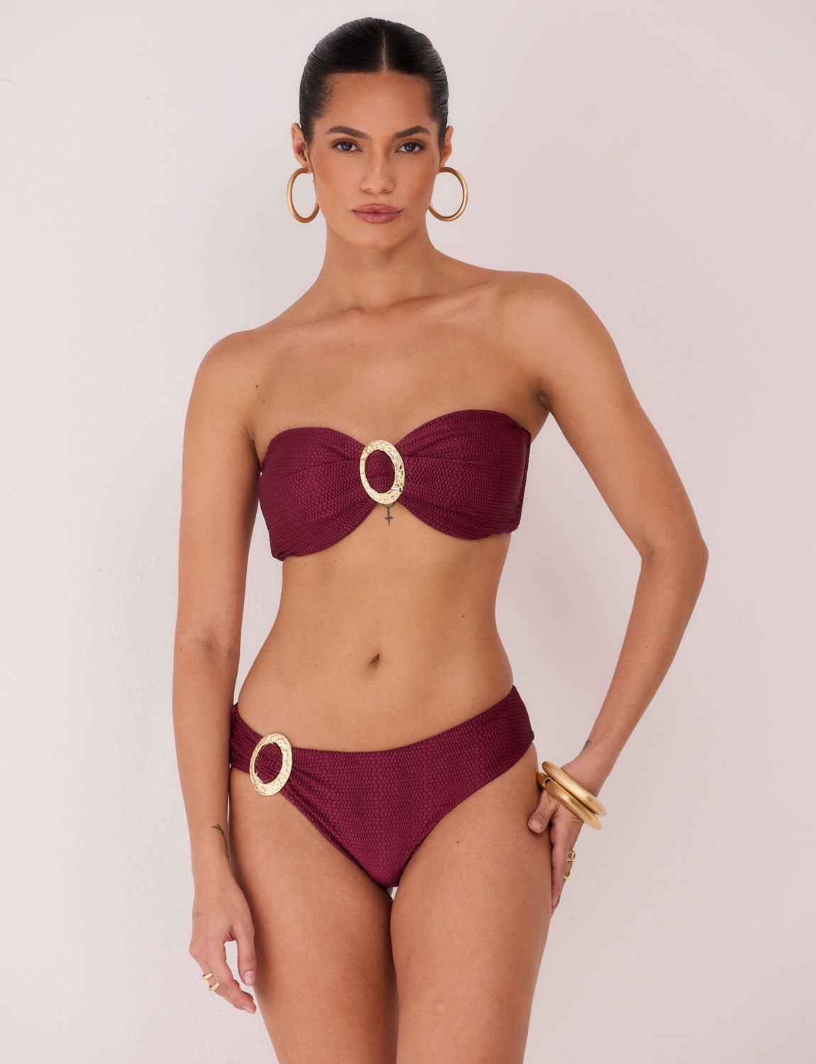 Modelo usando biquíni meia taça estruturado Burgundy em tecido Taipan texturizado; Costas do biquíni Bluebird com amarração e calcinha anatômica sofisticada