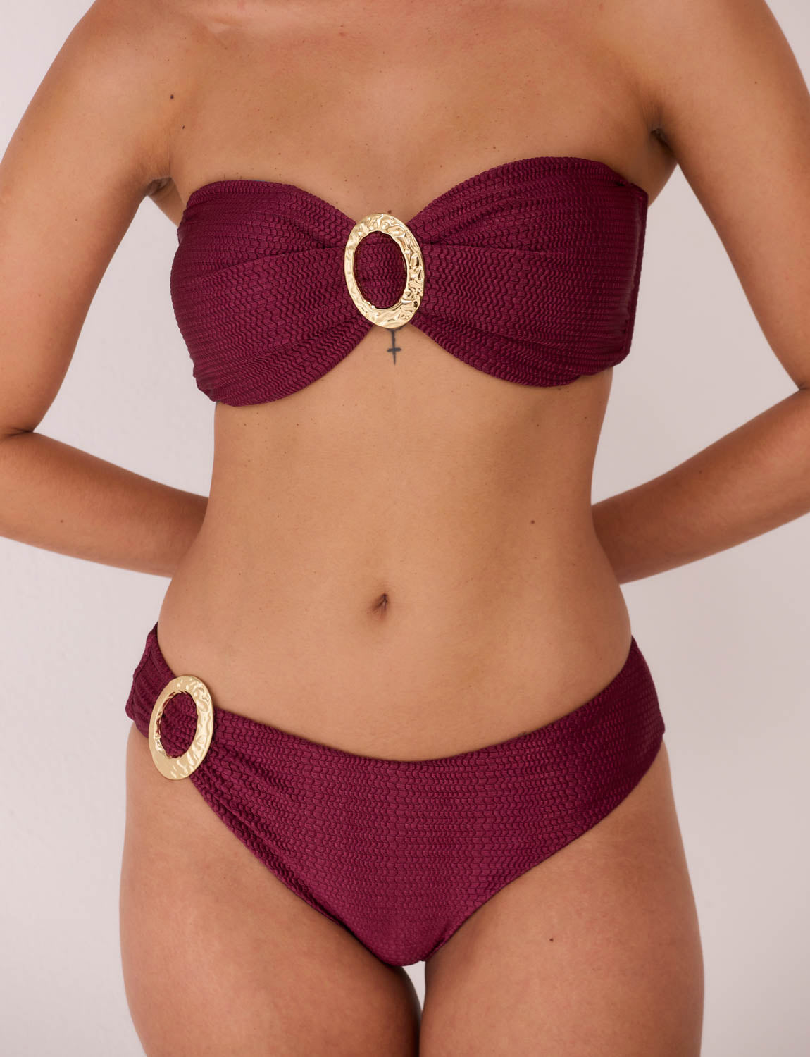 Modelo usando biquíni meia taça estruturado Burgundy em tecido Taipan texturizado; Costas do biquíni Bluebird com amarração e calcinha anatômica sofisticada