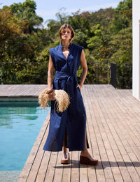 Mulher usando vestido longo azul marinho Kalini com cinto em composição sofisticada de resortwear