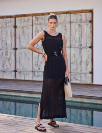 Mulher usando vestido regata preto em renda com cinto e fivela banhada a ouro em composição sofisticada de resortwear.