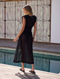 vista traseira de mulher usando vestido midi de renda preta com cinto e fivela dourada em look resortwear