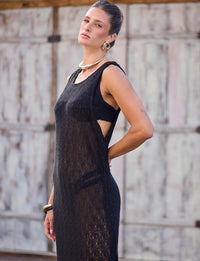 Vista traseira de mulher usando vestido longo de renda preta da Kalini com cinto e fivela banhada a ouro.